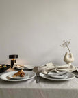 Elegant dining table set with white porcelain plates, soft lace edges, and decorative elements evoking nostalgia and sophistication.