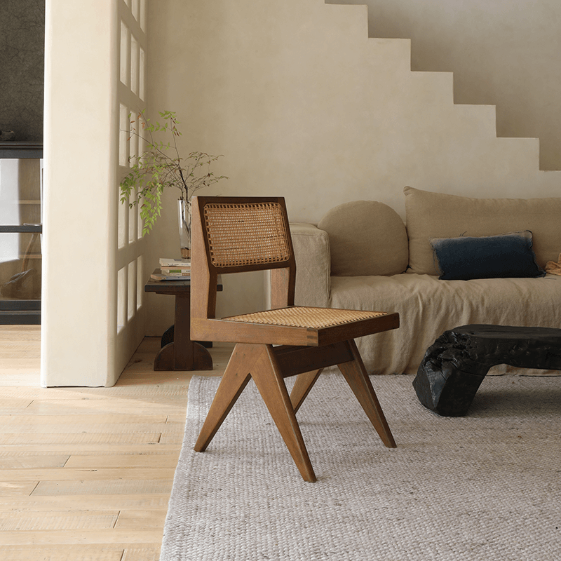 Wood-mounted dining chair with rattan weaving in a cozy living room setting, featuring teak construction and hand-crafted design.