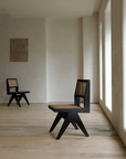 Elegant hand-made rattan wood-mounted dining chairs with teak wood and natural weaving in a minimalist room setting.