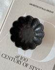 Black Rinka Bowl 12cm from Kaneko Kohyo on a book, showcasing its delicate porcelain and flower-inspired design.