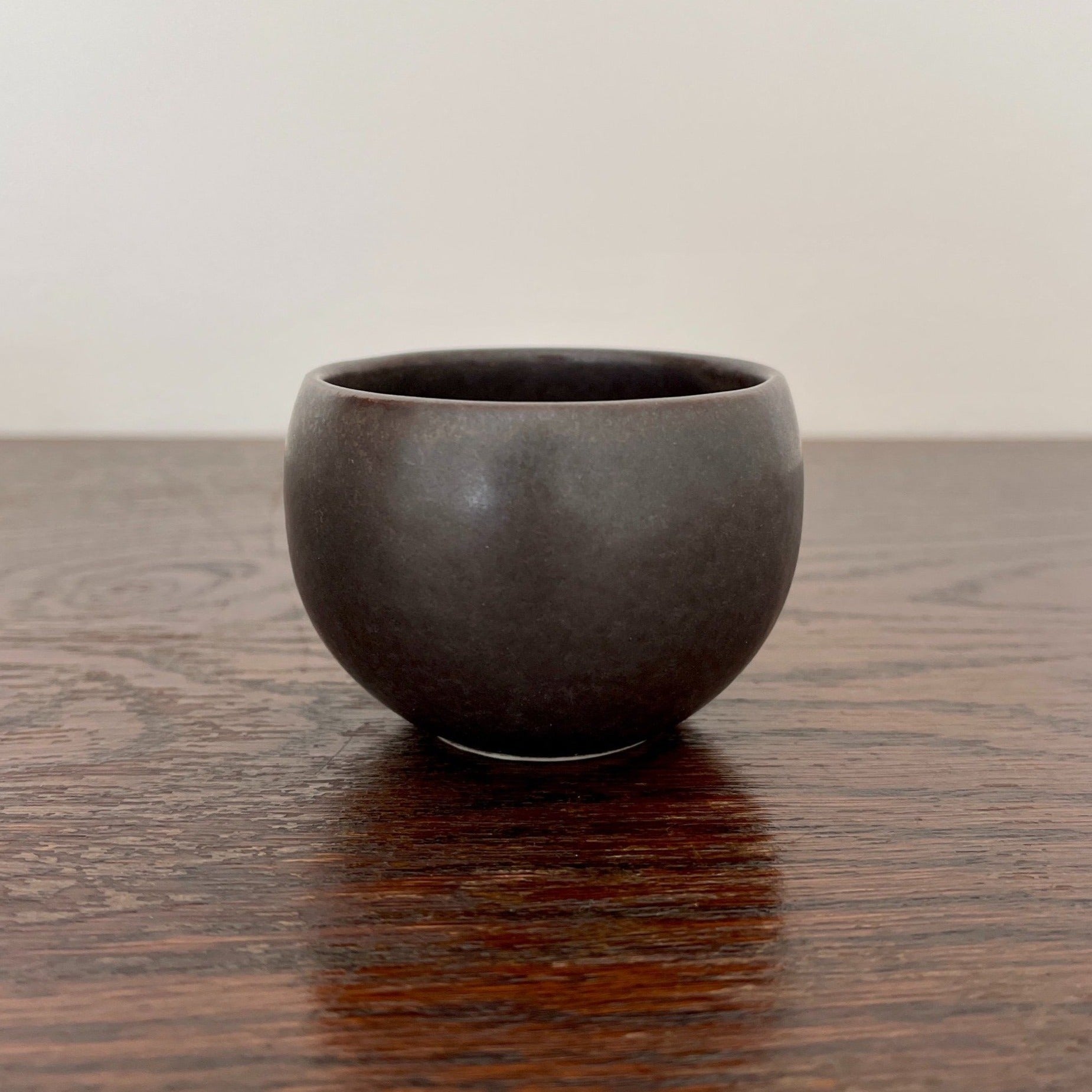 Matte black Rila Tea Cup from Minowares by Kaneko Kohyo, perfect for tea or single-serve dishes, 6.5cm diameter, on wooden surface.