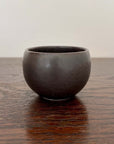 Matte black Rila Tea Cup from Minowares by Kaneko Kohyo, perfect for tea or single-serve dishes, 6.5cm diameter, on wooden surface.