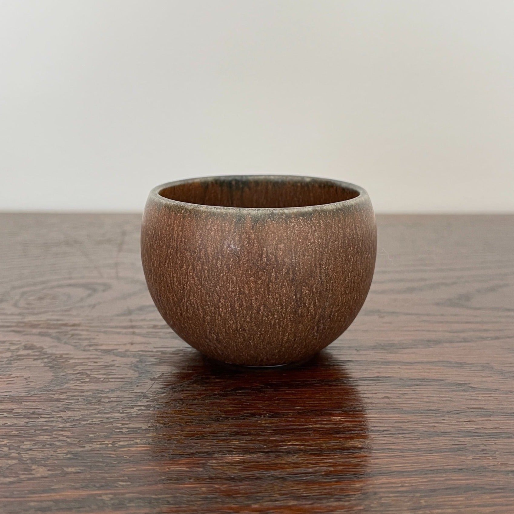 Brown Rila Tea Cup by Kaneko Kohyo on wooden table, textured and compact, ideal for tea, single-serve dishes, desserts. Diameter: 6.5cm.