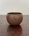 Brown Rila Tea Cup by Kaneko Kohyo on wooden table, textured and compact, ideal for tea, single-serve dishes, desserts. Diameter: 6.5cm.