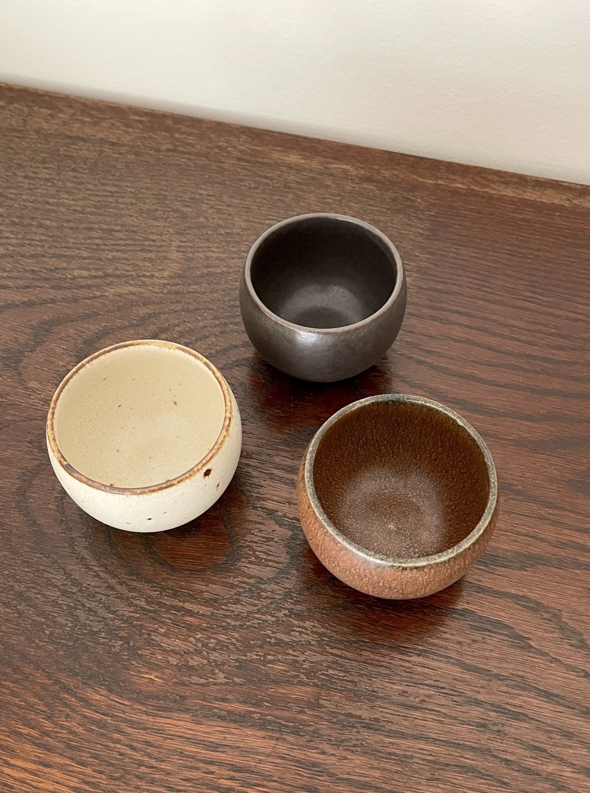 Three stackable Rila Tea Cups by Kaneko Kohyo, textured and matte colored, perfect for tea or desserts, displayed on a wooden surface.
