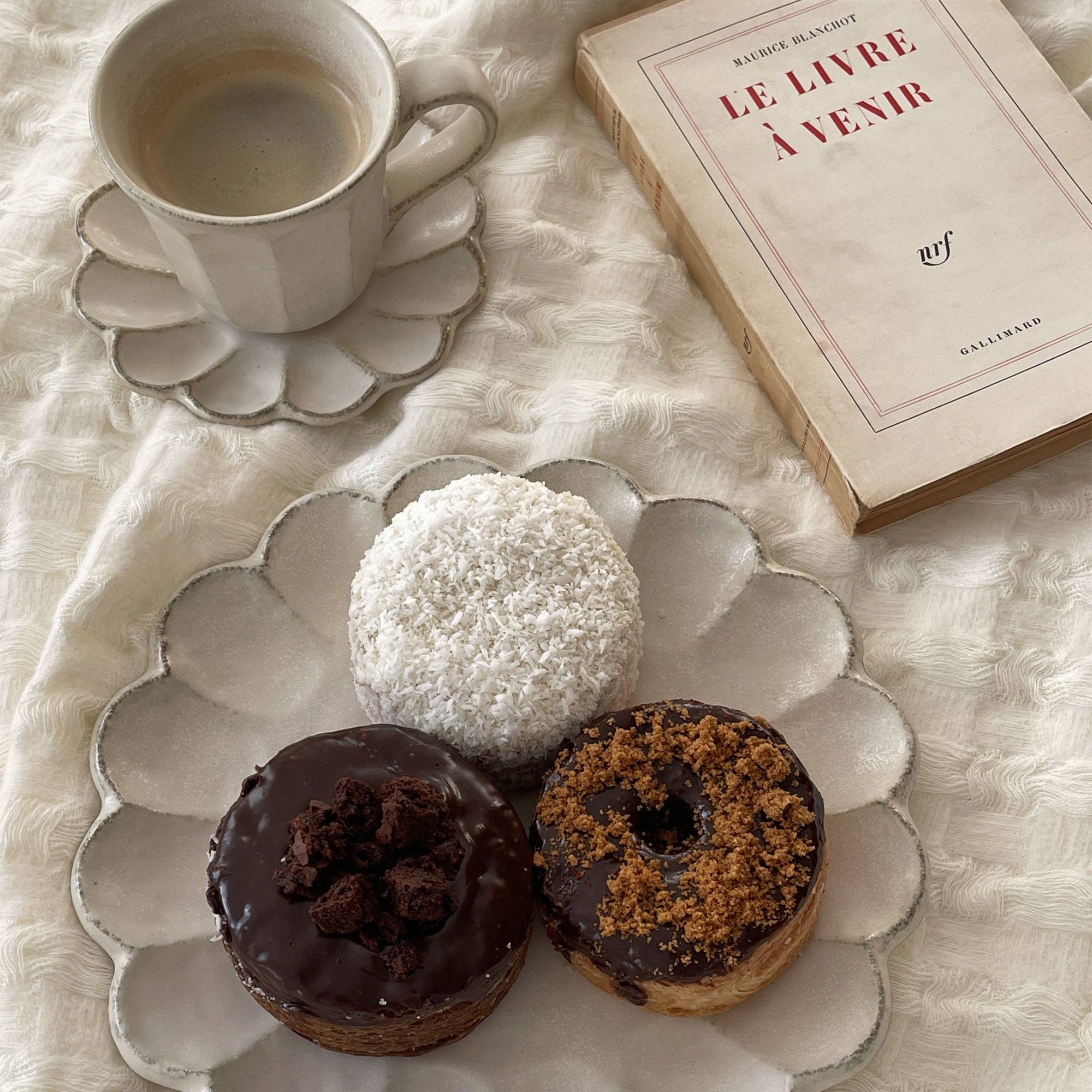 Rinka Mug and matching porcelain plate with donuts and a book on a textured cloth background.