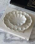 Handcrafted Rinka Oval Plates by Kaneko Kohyo in porcelain, showcasing a flower shape design, styled on a marble table with books.
