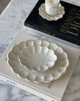 Elegant Rinka Oval Plates made of porcelain, styled on marble table with books and candle, perfect for enhancing table settings.