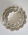 Stacked white porcelain Rinka bowls with flower-shaped design, showcasing delicate craftsmanship and elegance.