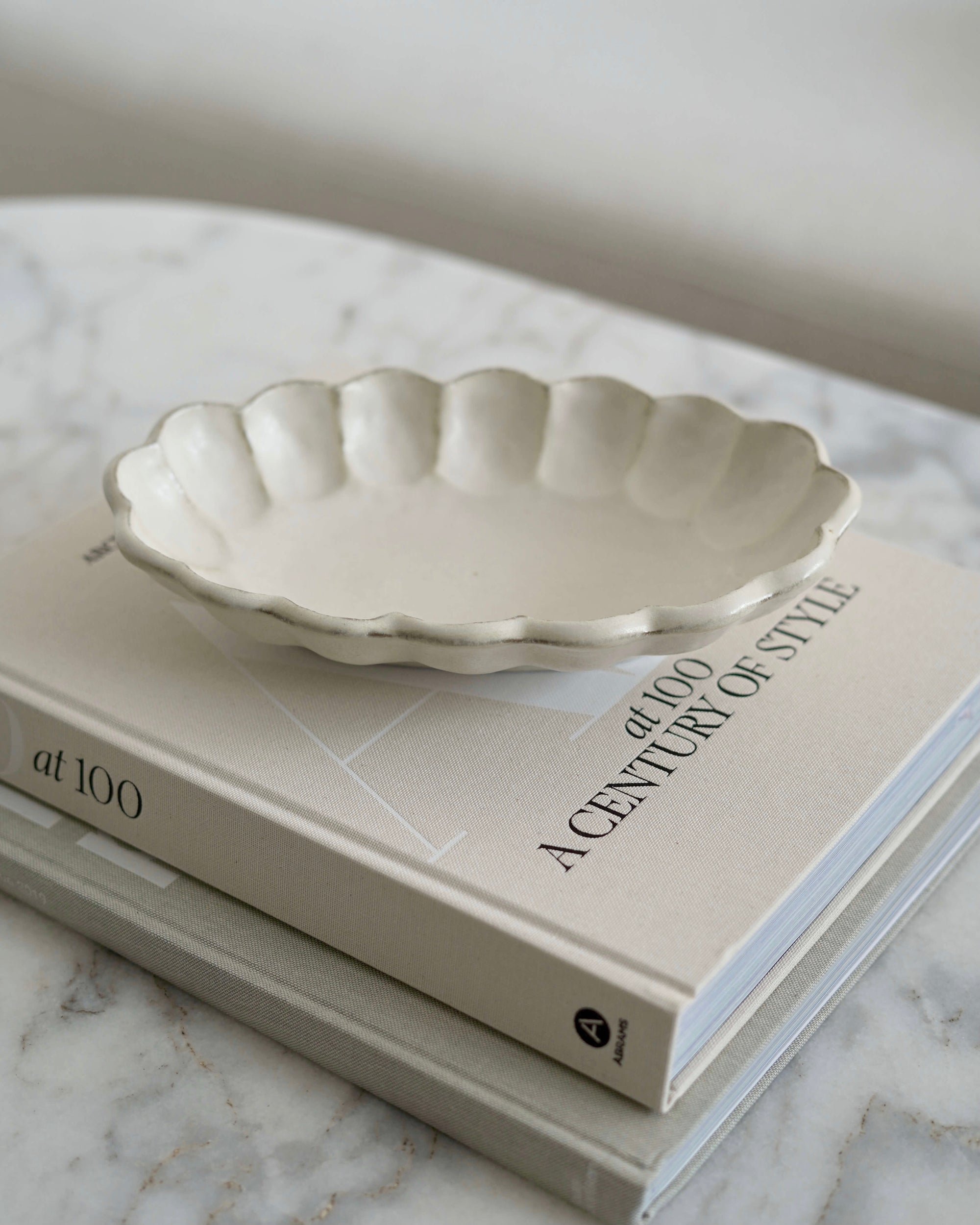 Rinka Oval Bowl 28cm by Kaneko Kohyo on a book, showcasing its delicate porcelain and flower shape design.
