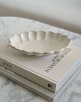 Rinka Oval Bowl 28cm by Kaneko Kohyo on a book, showcasing its delicate porcelain and flower shape design.