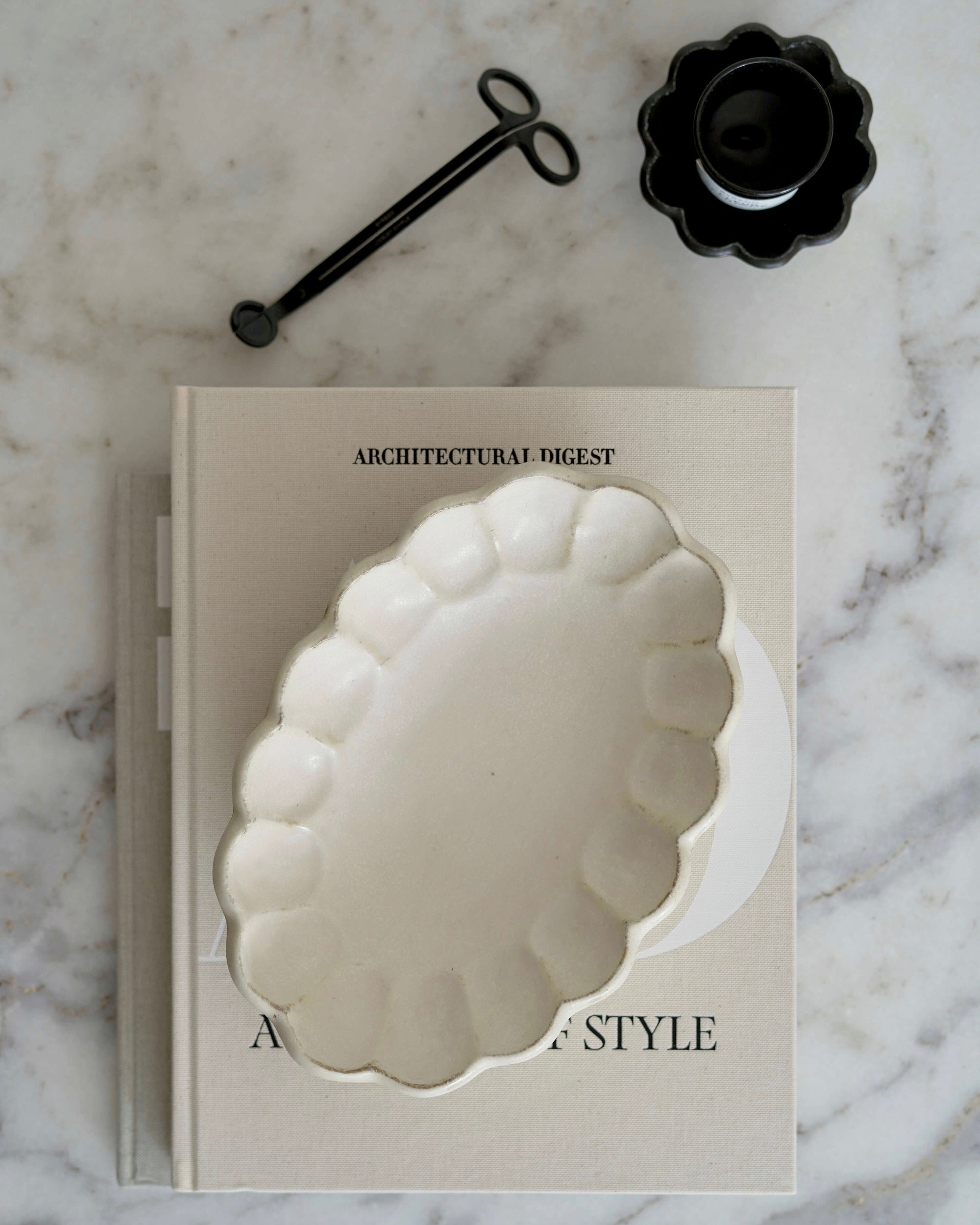 Rinka Oval Bowl 28cm made of delicate porcelain from Kaneko Kohyo, displayed on a marble surface with a book and black accessory.