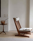 Nakajima George reclining chair made of teak wood and rattan, with open book, adding elegance and a romantic vibe to the room.