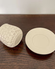 Elegant Shinogi Cup and Saucer set from Yoshida Pottery, featuring nature-inspired patterns, displayed on a wooden table.