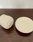 Elegant Shinogi Cup and Saucer set from Yoshida Pottery, featuring nature-inspired patterns, displayed on a wooden table.