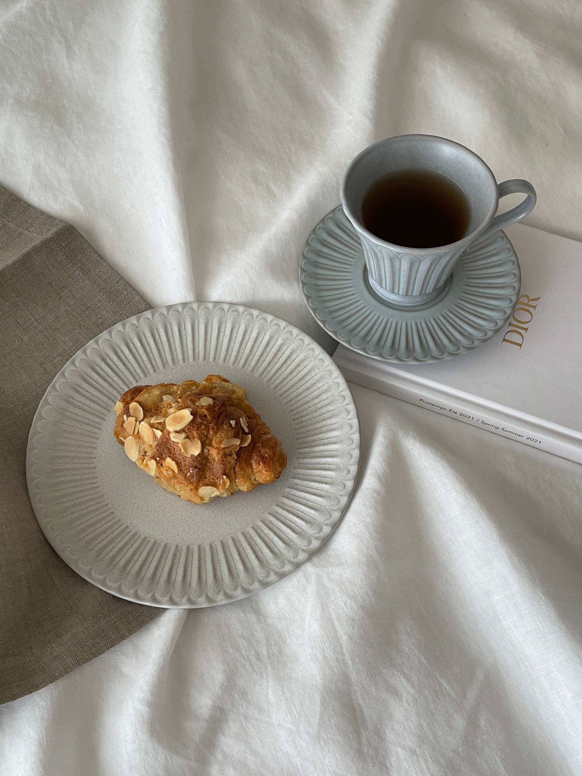 Elegant Storia Plate 20cm with croissant, paired with a porcelain cup of coffee, showcasing antique-inspired design.