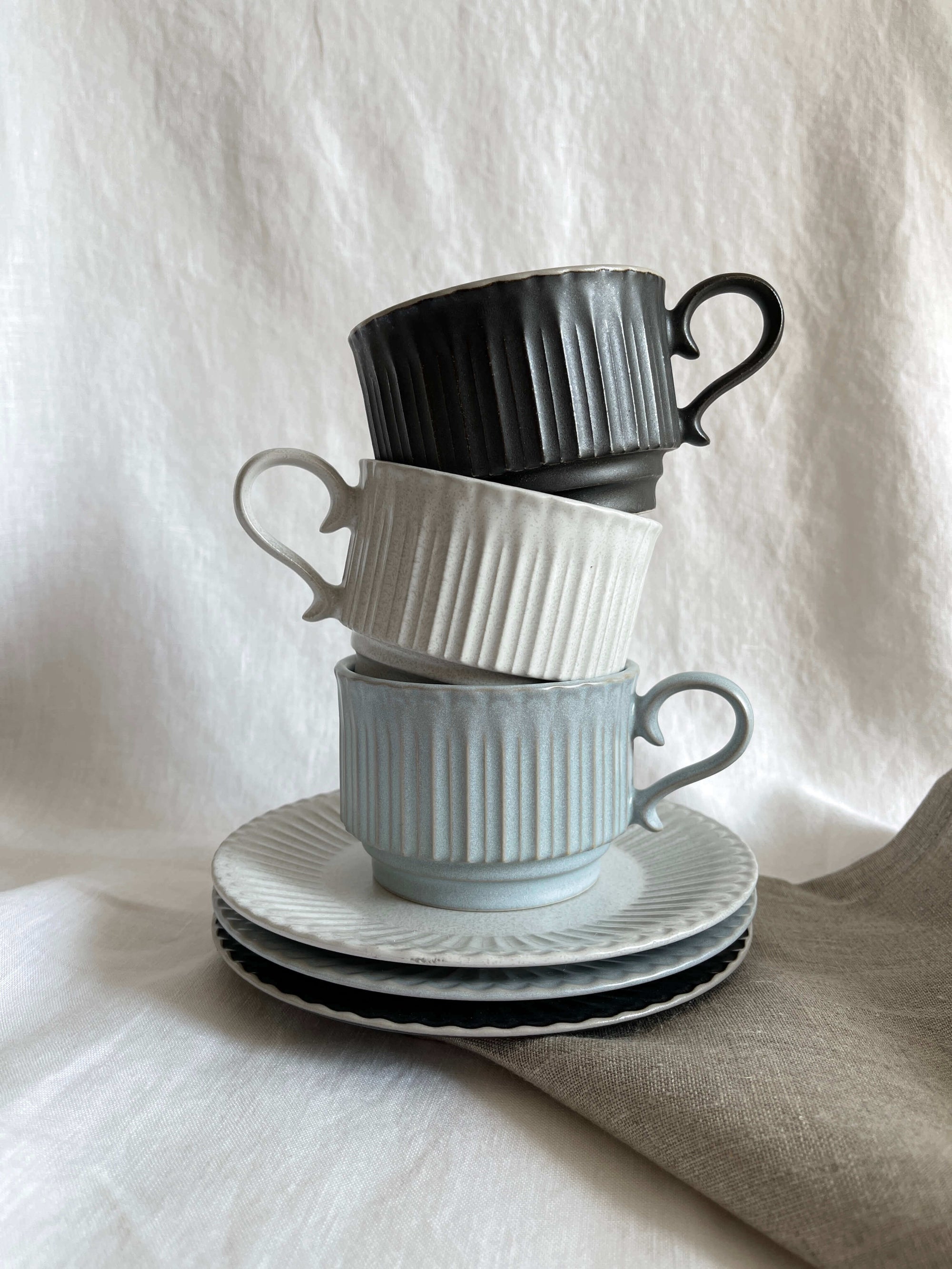 Storia Coffee Cup & Saucer with soft lace edges and flecked finish, inspired by antique European design, stack of three cups.