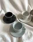 Storia coffee cup and saucer set in black, white, and gray, showcasing European-inspired design with a soft lace texture and flecked finish.