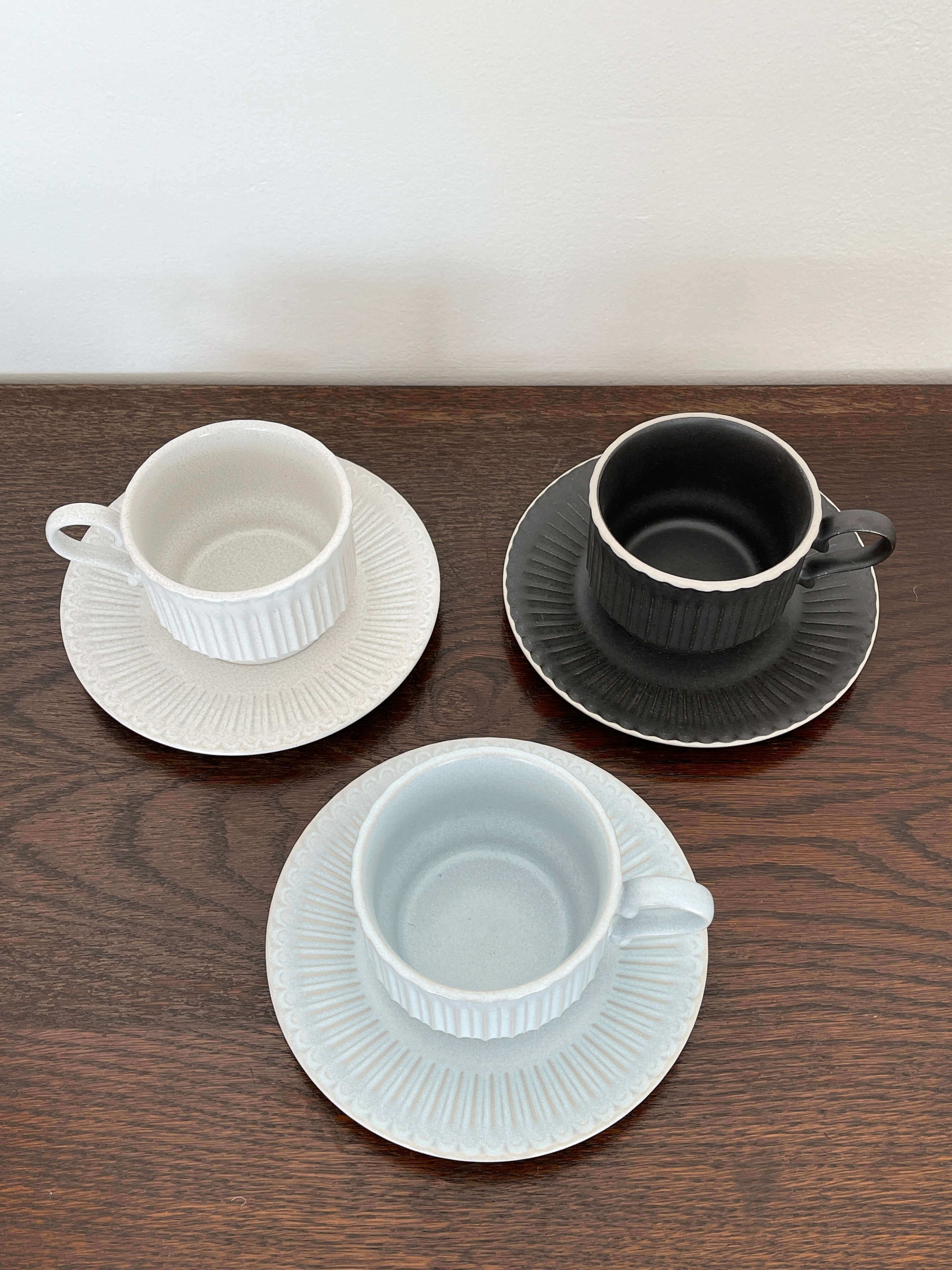 Three Storia coffee cups and saucers with European design on a wooden surface, featuring flecked lacquer finish from Koyo, Japan.