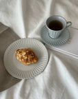Elegant Storia Plate 20cm with croissant, paired with a porcelain cup of coffee, showcasing antique-inspired design.