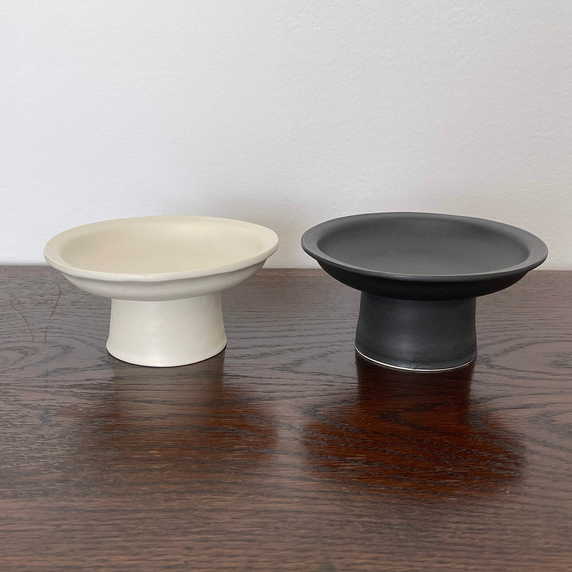Modern Japanese ceramic tall plates by Yoshida Pottery in black and white on a wooden table, showcasing elegant nature-inspired design.