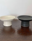 Modern Japanese ceramic tall plates by Yoshida Pottery in black and white on a wooden table, showcasing elegant nature-inspired design.