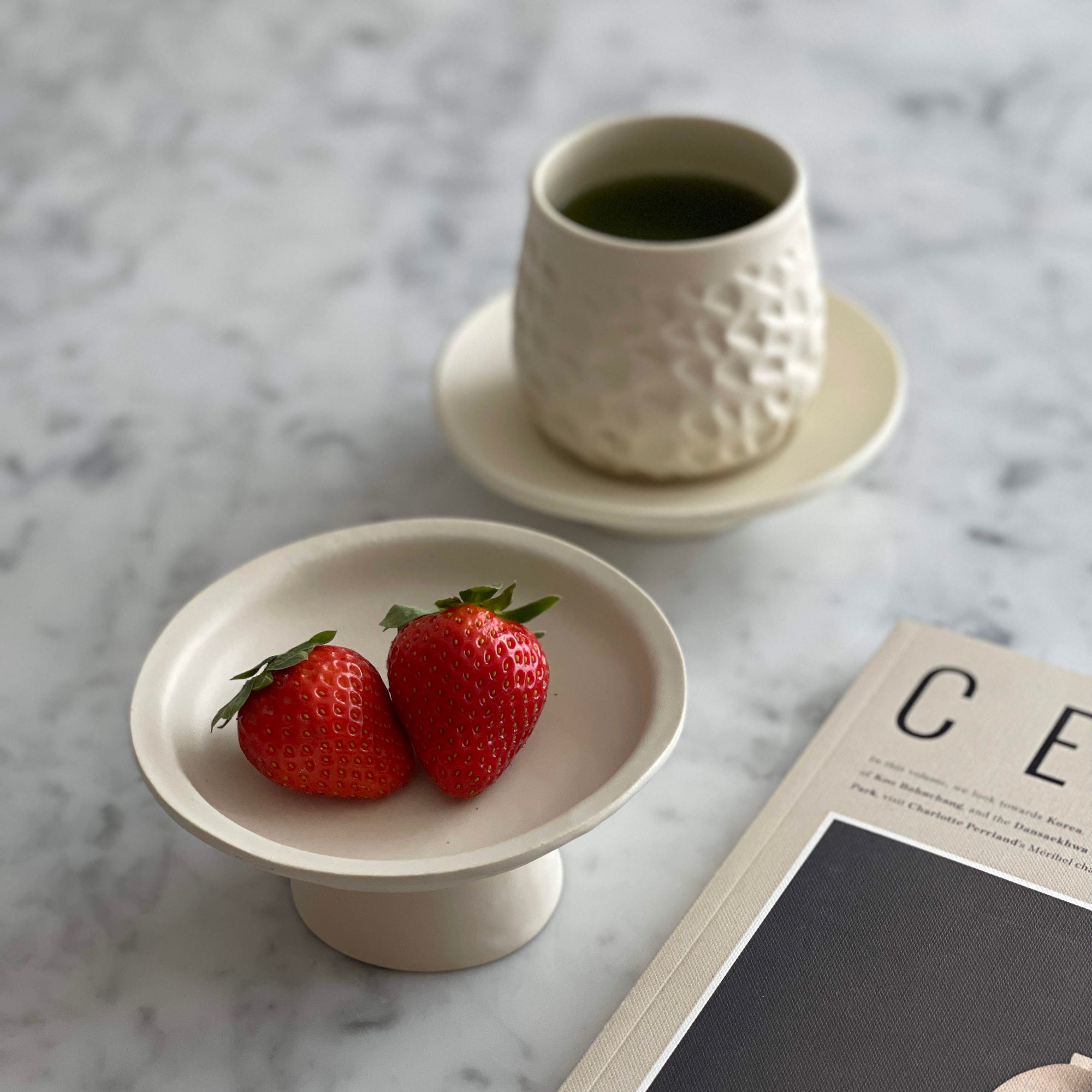Elegant Yoshida Pottery Tall Plate with strawberries and textured cup on marble table, showcasing nature-inspired design.