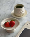 Elegant Yoshida Pottery Tall Plate with strawberries and textured cup on marble table, showcasing nature-inspired design.
