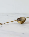 Handwoven brass tea filter for loose leaf tea on a marble surface.