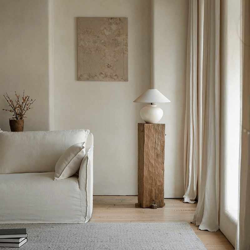 Wabi-Sabi style handmade table lamp with milky white pottery base and linen shade, set in a serene living room with natural decor.