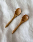 Two wooden teaspoons on a white cloth, perfect for tea or coffee, made from natural wood, 12.1cm in length.