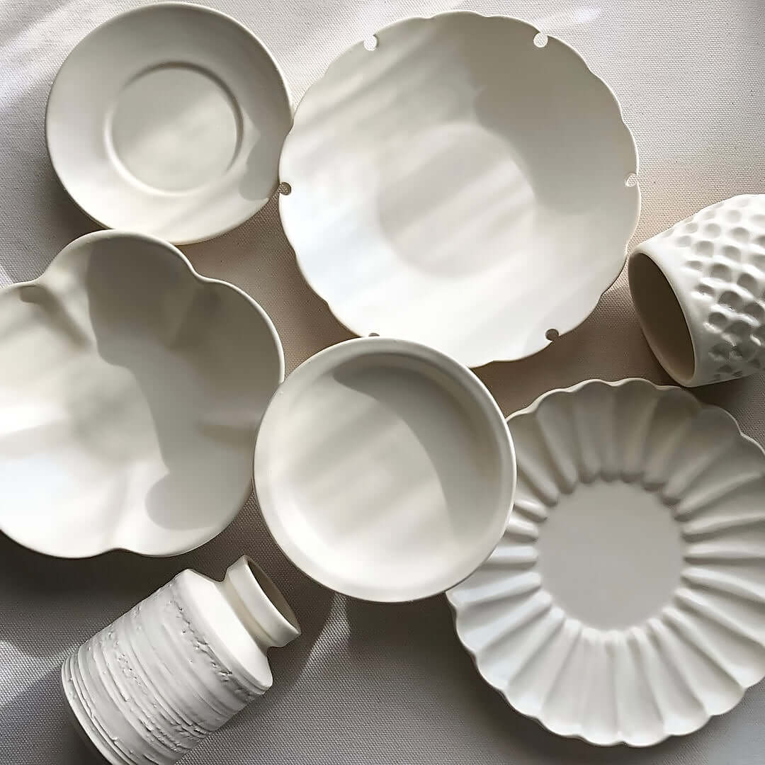 Yoshida Bundle pottery collection featuring elegant white plates, bowls, cups, saucers, and vases by Masakazu Yoshida on display.