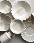 Yoshida Bundle pottery collection featuring elegant white plates, bowls, cups, saucers, and vases by Masakazu Yoshida on display.
