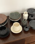 Assorted Yoshida Pottery Collection bowls and cups elegantly displayed on a wooden surface, showcasing nature-inspired patterns.