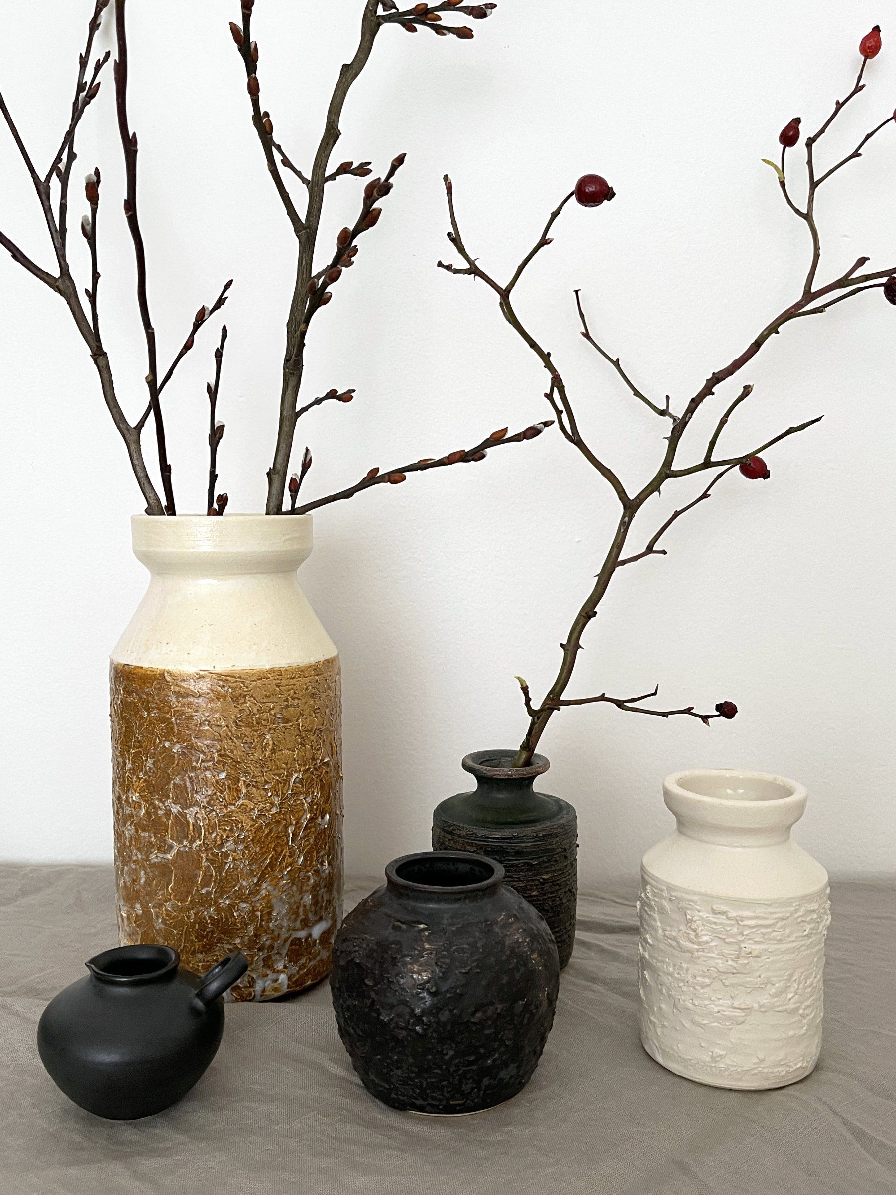 Elegant ceramic vases from the Yoshida Pottery Collection with nature-inspired designs, adorned with branches on a neutral background.