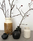 Elegant ceramic vases from the Yoshida Pottery Collection with nature-inspired designs, adorned with branches on a neutral background.