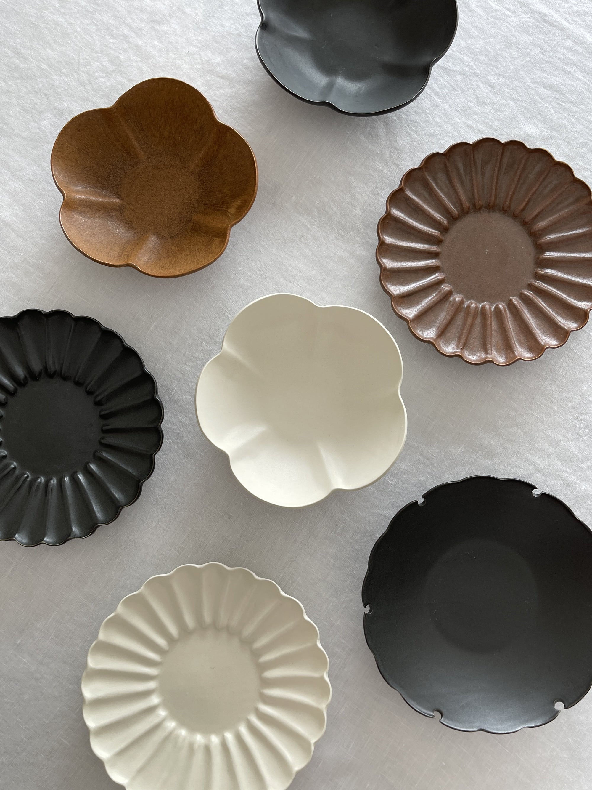 Assorted Rinka Plates from Yoshida Pottery, featuring elegant, nature-inspired patterns in various colors displayed on a white surface.