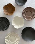 Assorted Rinka Plates from Yoshida Pottery, featuring elegant, nature-inspired patterns in various colors displayed on a white surface.