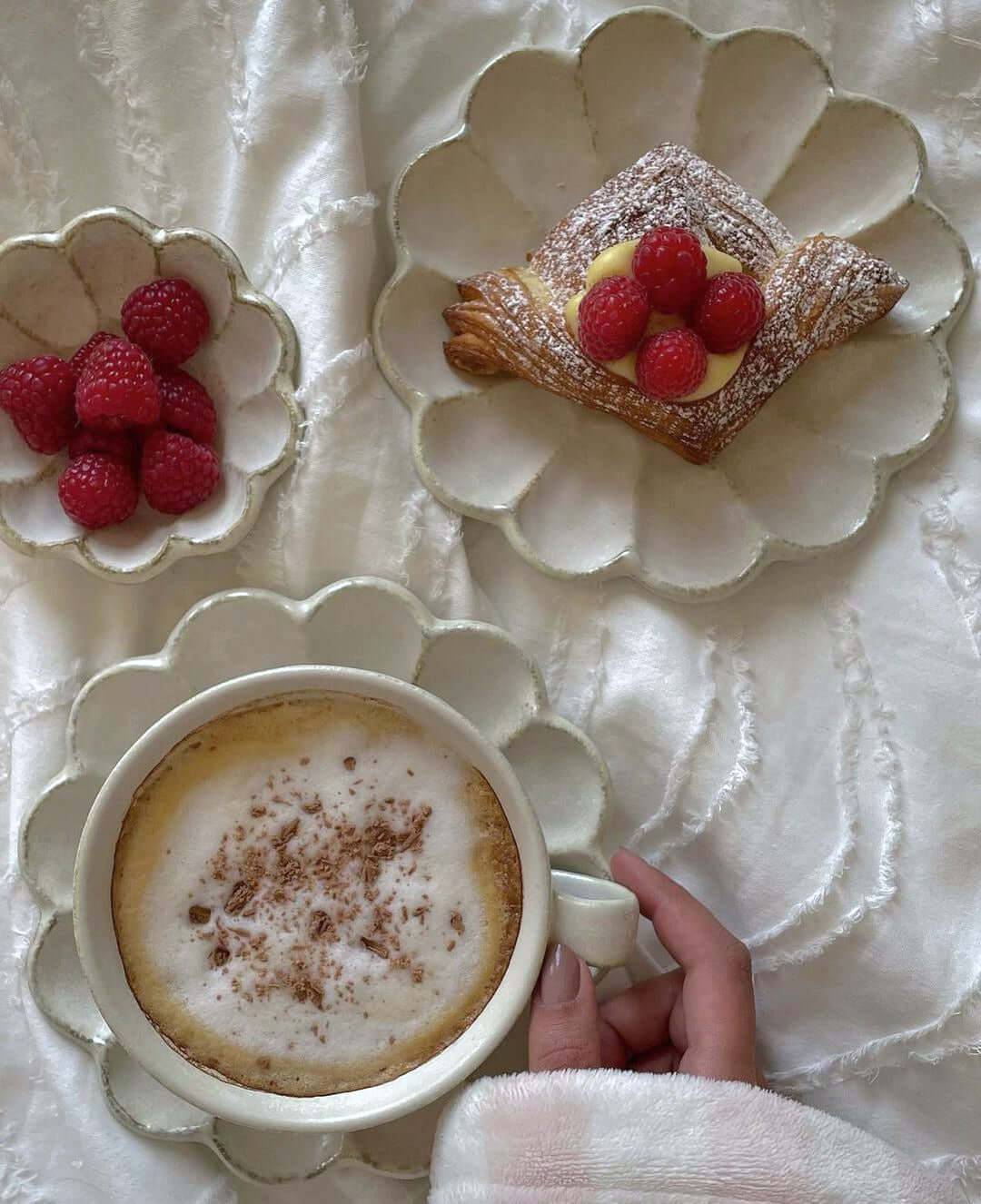 Elegant dining set with flower petal design, featuring coffee, pastry, and raspberries on handcrafted Japanese plates by Kaneko Kohyo.