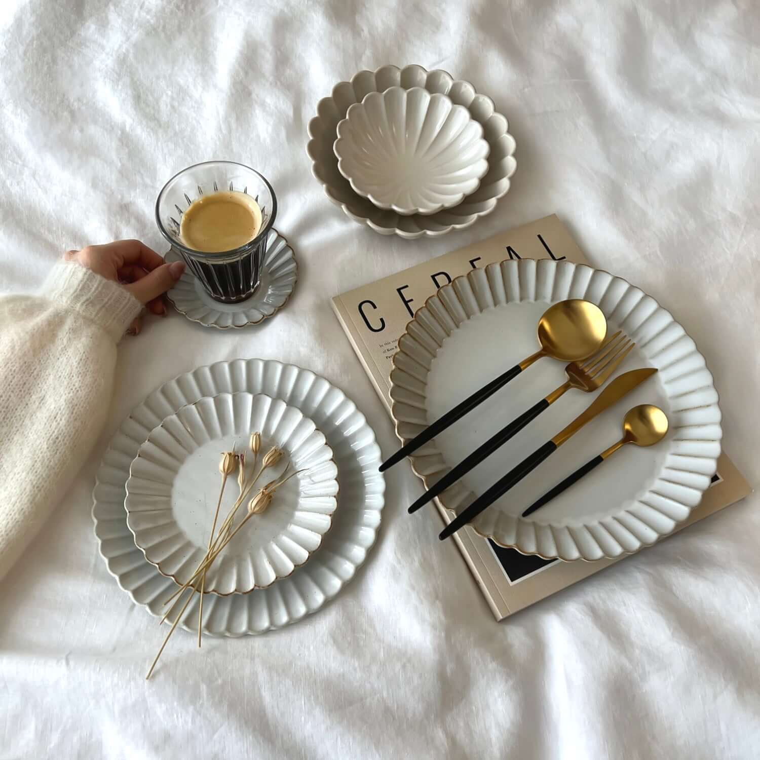 Elegant Marumitsu Barbarie plates with petal-like rims, set with gold cutlery and coffee on a magazine, enhancing dining sophistication