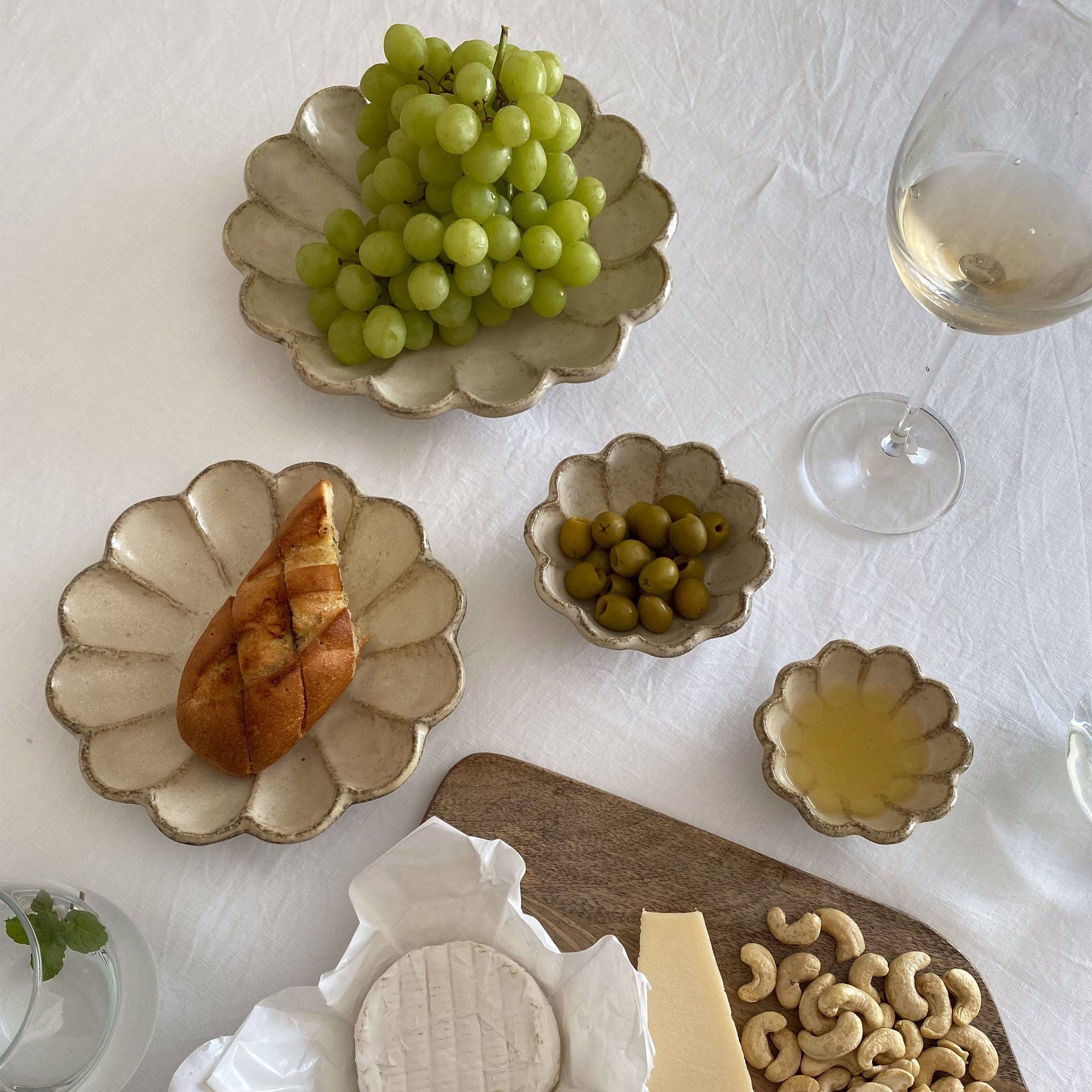 Elegant table setting with Kaneko Kohyo Rinka porcelain plates, showcasing grapes, bread, olives, and a glass of white wine.