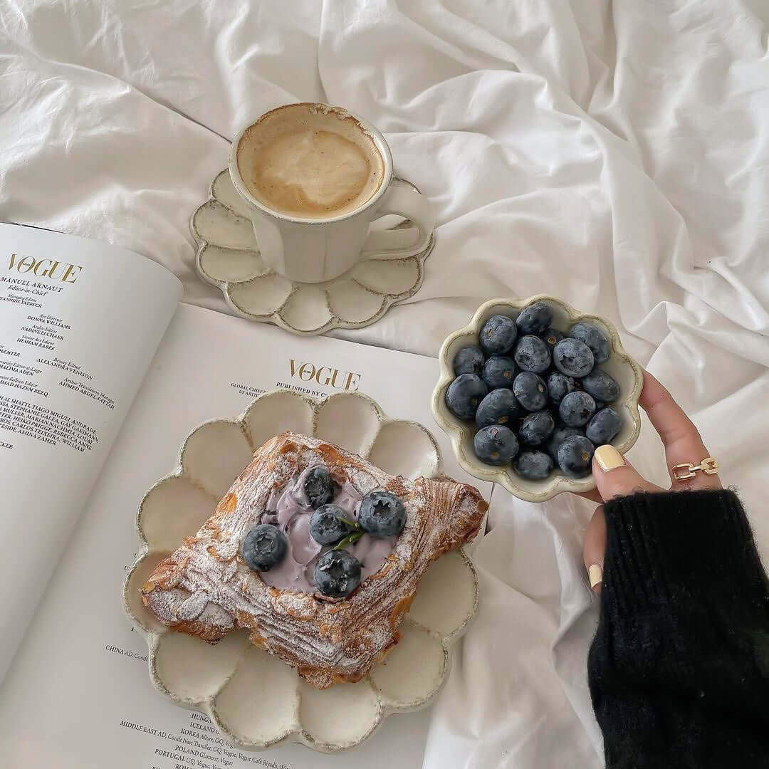 Elegant breakfast setup with coffee, pastry, and blueberries on nature-inspired Rinka plates by Kaneko Kohyo, enhancing cozy dining ambiance.