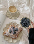 Elegant breakfast setup with coffee, pastry, and blueberries on nature-inspired Rinka plates by Kaneko Kohyo, enhancing cozy dining ambiance.