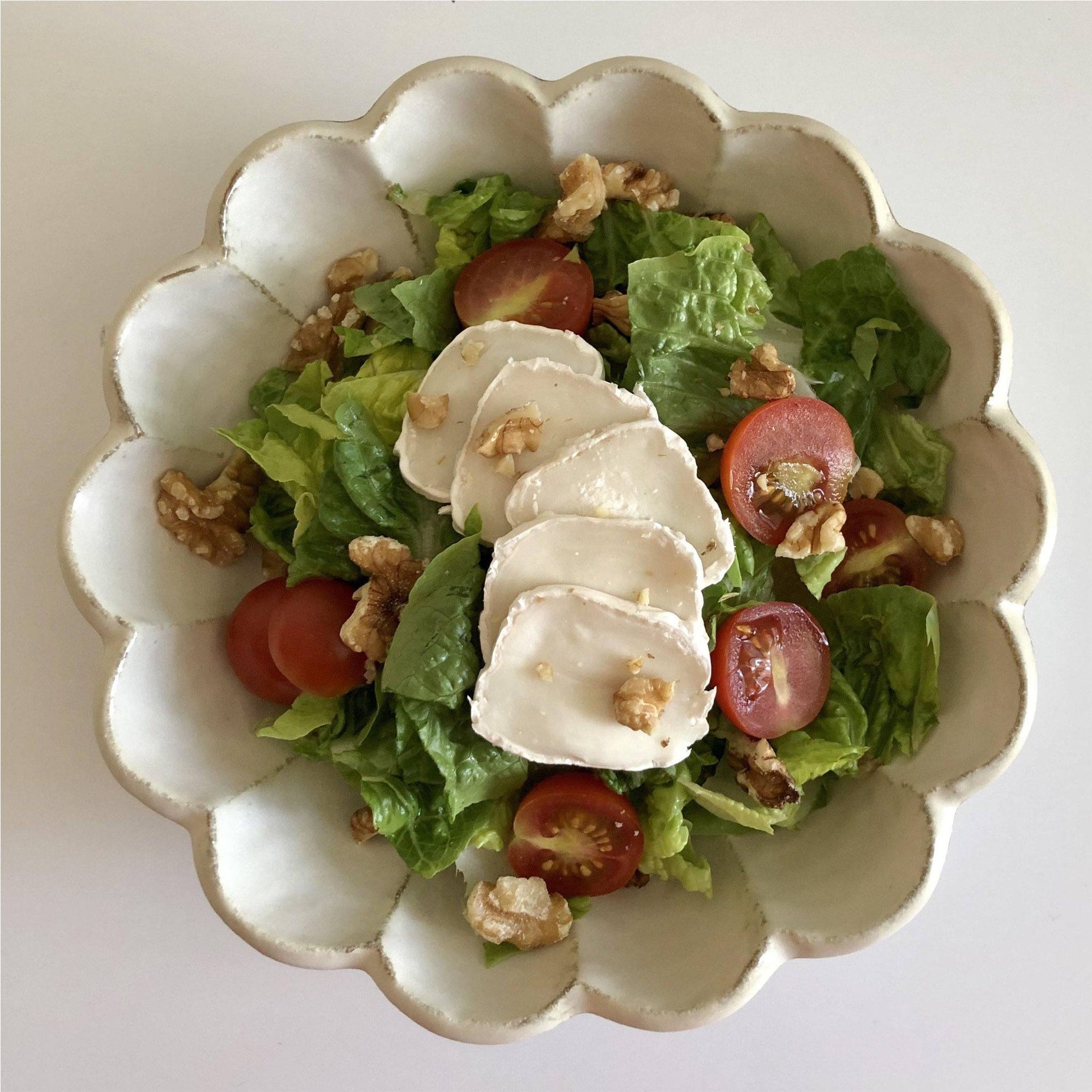 Rinka Bowl 21cm with fresh salad, featuring lettuce, cherry tomatoes, goat cheese, and walnuts, showcasing its flower-shaped porcelain design.