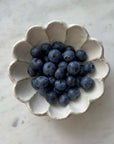 Scalloped white Rinka bowl with fresh blueberries on marble surface.