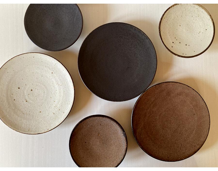 Assorted textured ceramic plates in neutral tones, crafted by Kaneko Kohei, showcasing Japanese porcelain artistry.