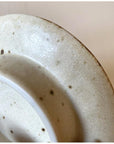 Close-up of a tastefully textured porcelain plate by Kaneko Kohyo, showcasing a warm matte color and rough texture.