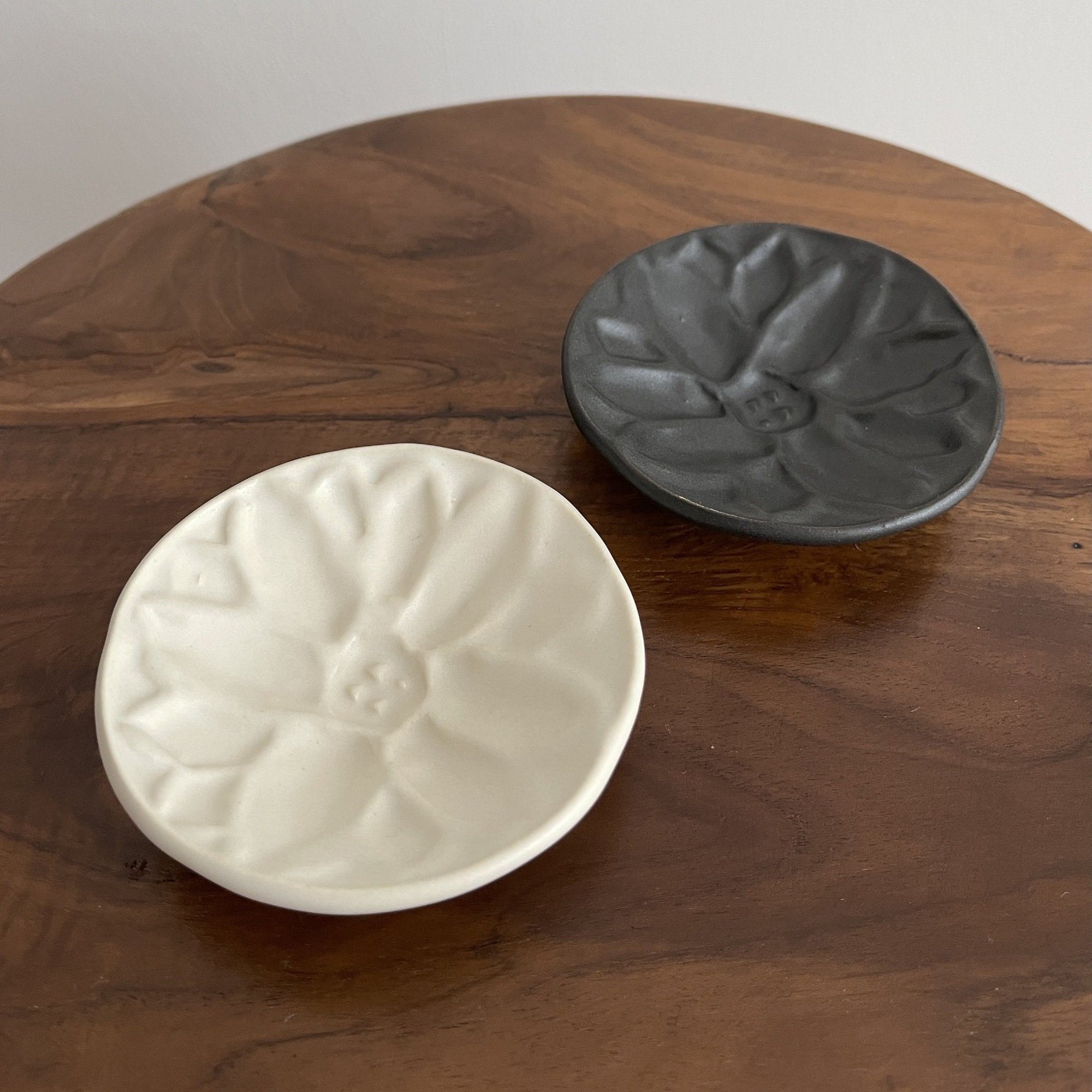 Elegant black and white Mame Plate set from Yoshida Pottery Collection on a wooden table, showcasing nature-inspired patterns.