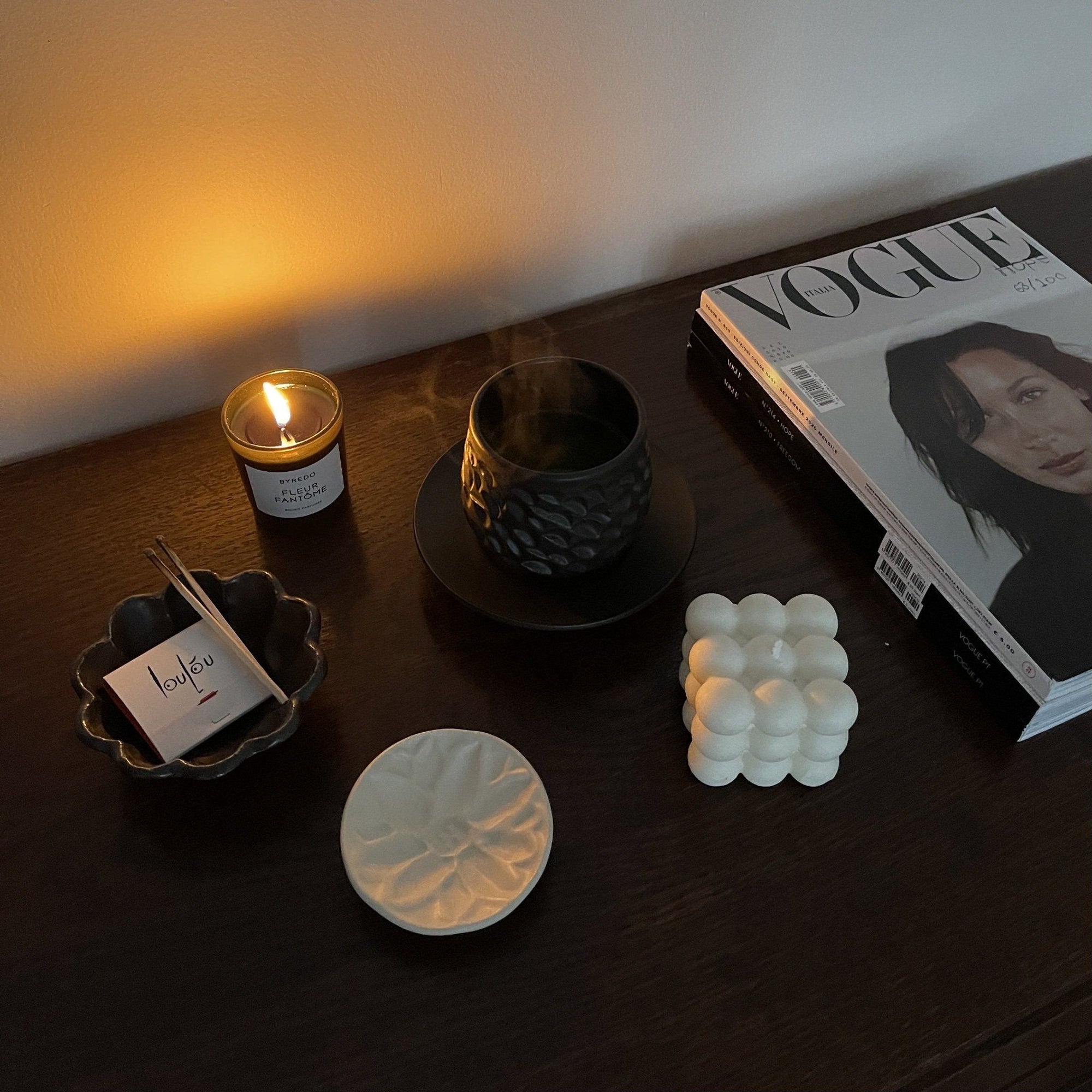 Elegant table setting with candle, cup, magazines, and decorative plates from Yoshida Pottery Collection by Masakazu Yoshida.