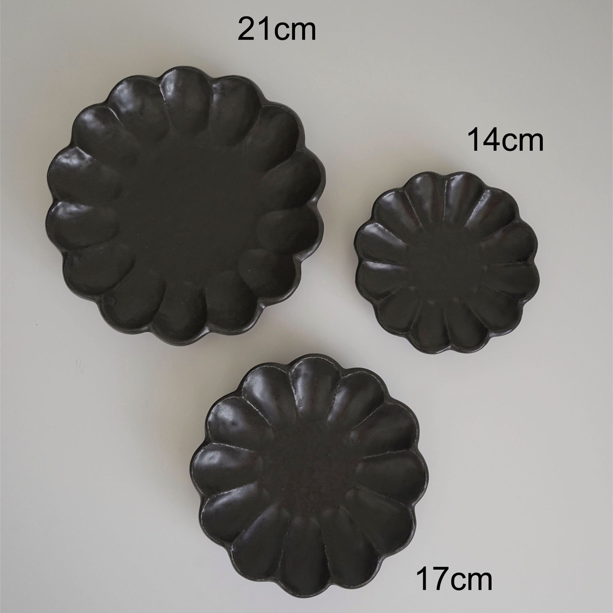 Three black Rinka plates by Kaneko Kohyo in sizes 21cm, 17cm, and 14cm, showcasing elegant handcrafted porcelain design.